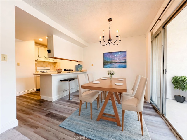 dining area featuring hardwood / wood-style floors, a textured ceiling, and an inviting chandelier