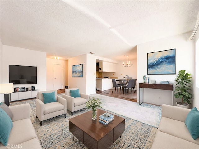 living room featuring light hardwood / wood-style floors, a textured ceiling, and a notable chandelier