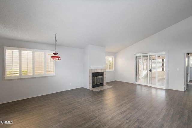 unfurnished living room with a textured ceiling, lofted ceiling, dark wood-type flooring, and a tile fireplace