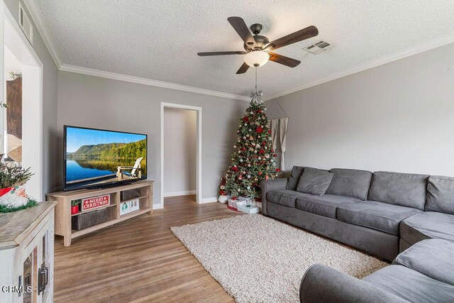 living room with hardwood / wood-style floors, a textured ceiling, ceiling fan, and crown molding