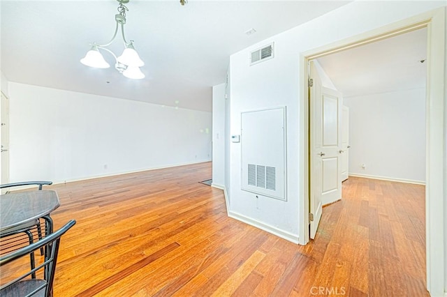 spare room with a notable chandelier and light hardwood / wood-style floors