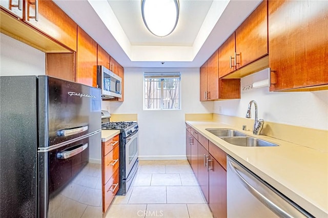 kitchen featuring a raised ceiling, light tile patterned floors, sink, and appliances with stainless steel finishes