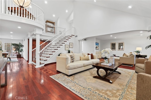 living room featuring wood-type flooring, decorative columns, and high vaulted ceiling