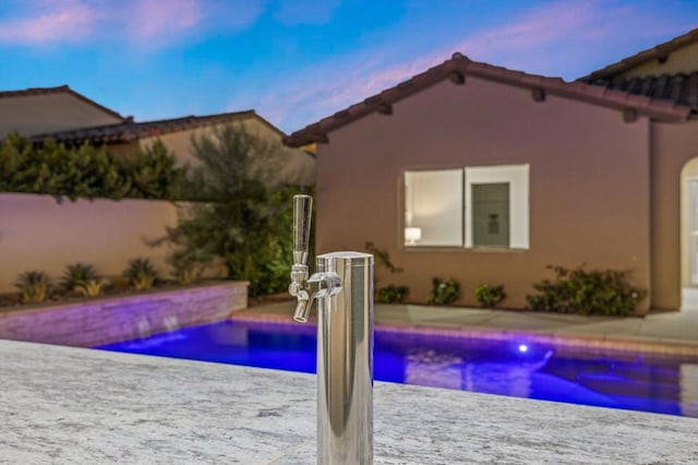 pool at dusk featuring a patio area