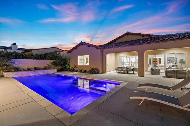 pool at dusk featuring a patio area, an in ground hot tub, and an outdoor living space