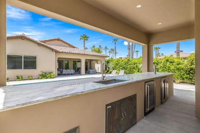 view of patio featuring exterior kitchen, sink, and beverage cooler