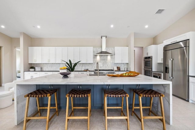 kitchen with wall chimney exhaust hood, a spacious island, and appliances with stainless steel finishes