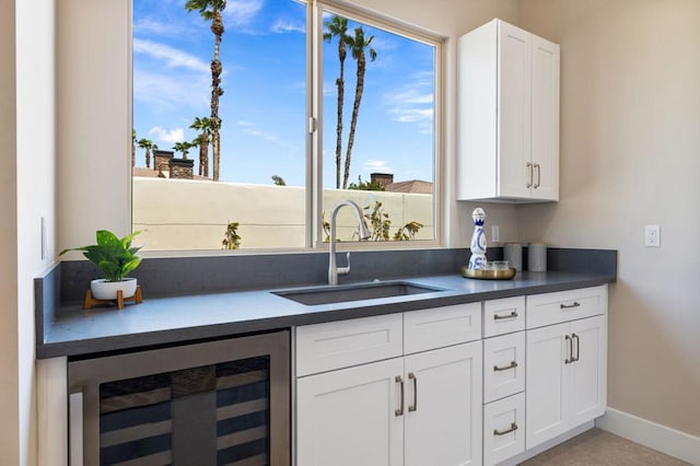 kitchen featuring white cabinets, beverage cooler, and sink