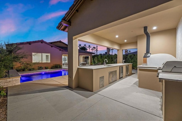 patio terrace at dusk featuring exterior kitchen, sink, and wine cooler