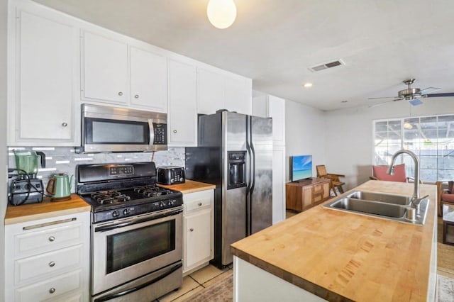 kitchen with white cabinetry, sink, stainless steel appliances, wooden counters, and light tile patterned flooring