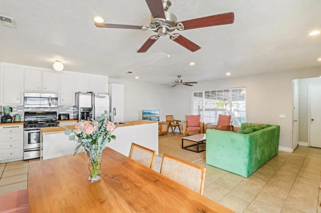 tiled dining room featuring ceiling fan and sink