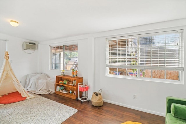 recreation room with dark hardwood / wood-style floors and an AC wall unit