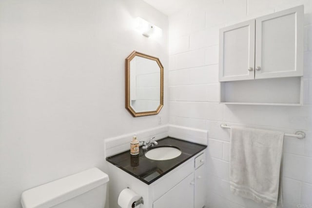 bathroom with vanity, tile walls, and toilet