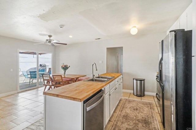 kitchen with white cabinetry, sink, stainless steel appliances, butcher block countertops, and a kitchen island with sink