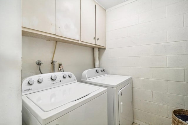 clothes washing area with washer and clothes dryer and cabinets