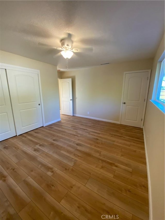 unfurnished bedroom with ceiling fan, a closet, and light hardwood / wood-style flooring