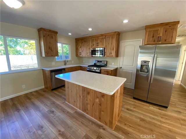 kitchen with a kitchen island, light hardwood / wood-style floors, sink, and appliances with stainless steel finishes