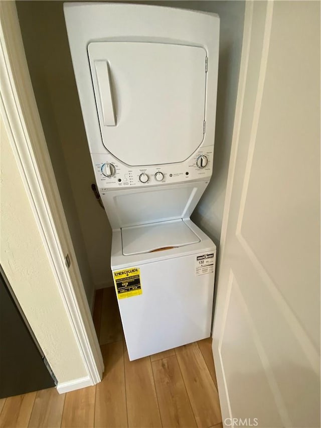 washroom with stacked washer / dryer and light hardwood / wood-style flooring