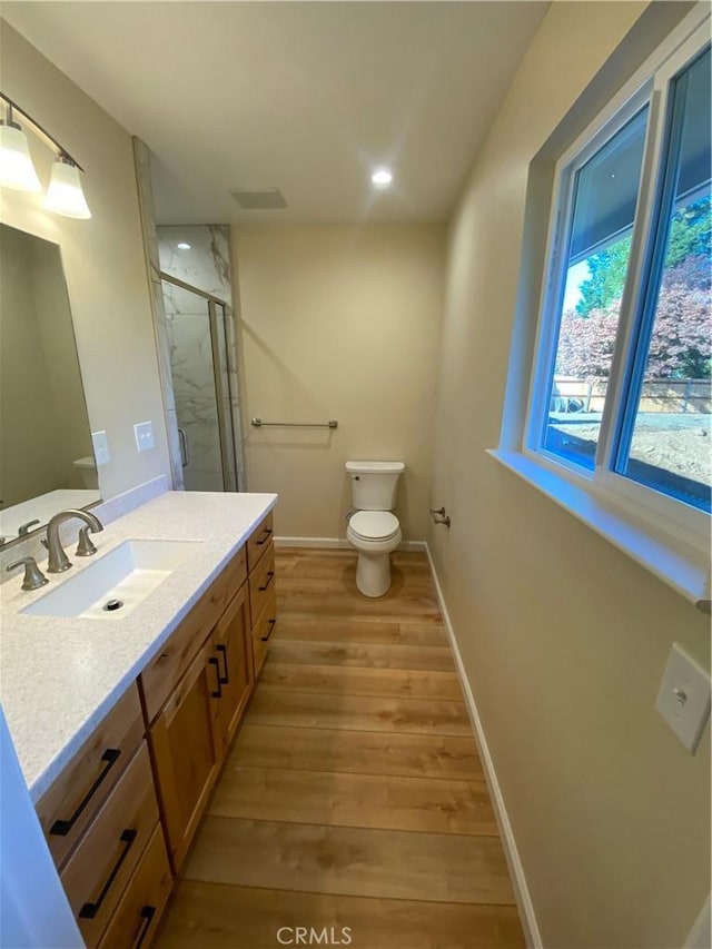 bathroom featuring hardwood / wood-style floors, vanity, toilet, and a shower with shower door