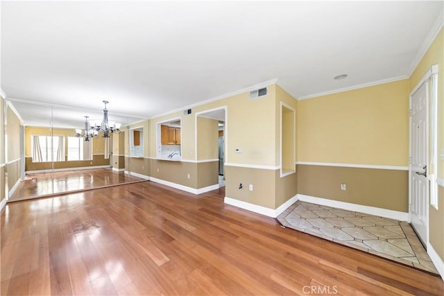 spare room with hardwood / wood-style floors, crown molding, and a chandelier