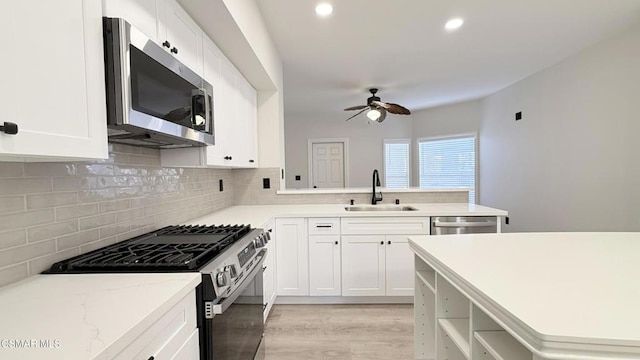 kitchen featuring ceiling fan, light hardwood / wood-style floors, sink, white cabinetry, and appliances with stainless steel finishes