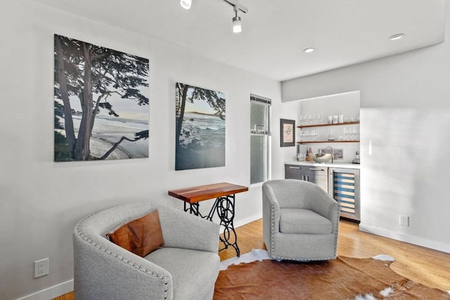 sitting room featuring wet bar, light hardwood / wood-style floors, and wine cooler