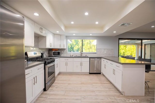 kitchen with kitchen peninsula, appliances with stainless steel finishes, white cabinetry, and a breakfast bar area