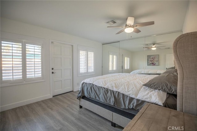 bedroom featuring hardwood / wood-style flooring, ceiling fan, and multiple windows