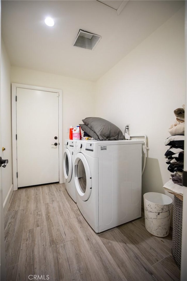 washroom featuring washing machine and dryer and light hardwood / wood-style flooring