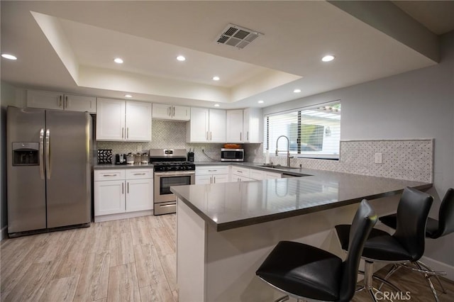 kitchen with sink, light hardwood / wood-style flooring, white cabinetry, kitchen peninsula, and stainless steel appliances