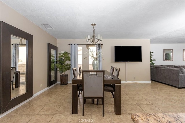 dining space featuring light tile patterned floors, a textured ceiling, and a notable chandelier