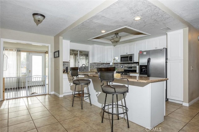 kitchen featuring white cabinets, a center island, stainless steel appliances, and stone counters