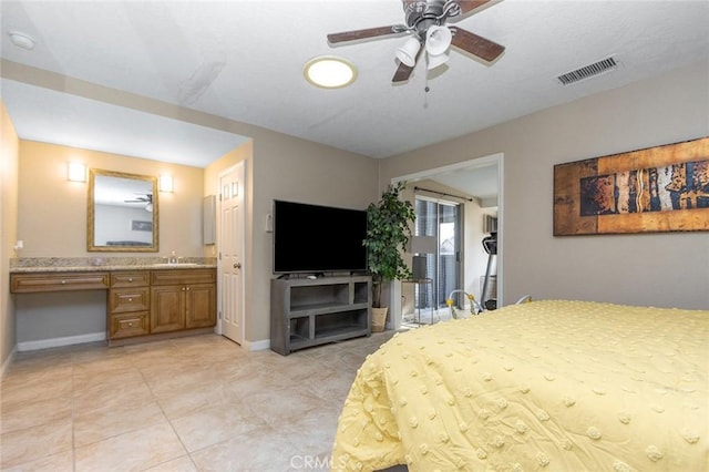 bedroom featuring sink, ceiling fan, built in desk, connected bathroom, and light tile patterned flooring