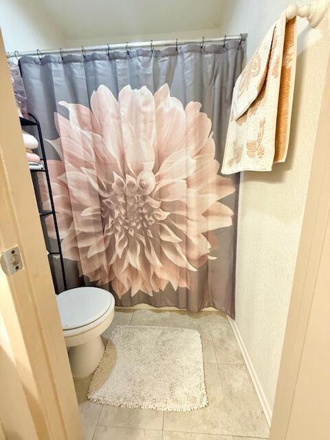 bathroom with walk in shower, tile patterned flooring, and toilet