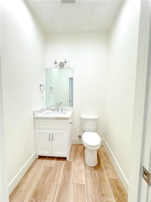 bathroom with vanity, hardwood / wood-style flooring, and toilet