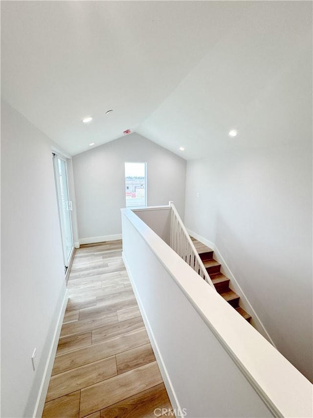 hall with light hardwood / wood-style floors and lofted ceiling