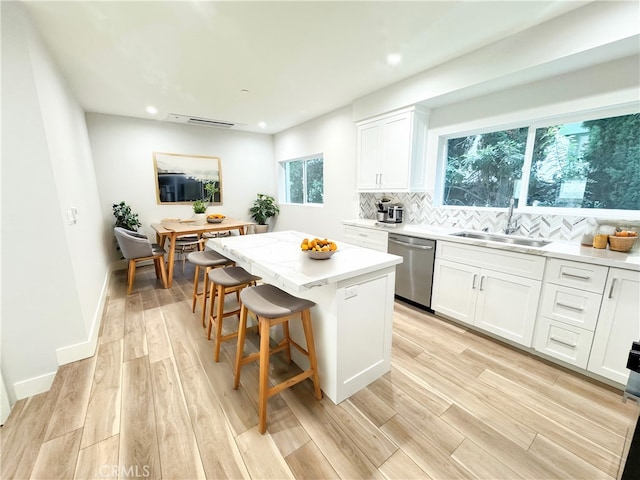 kitchen with dishwasher, a center island, sink, white cabinets, and light wood-type flooring