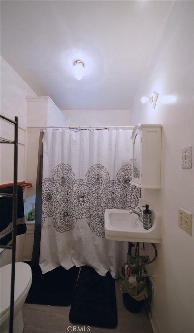 bathroom with curtained shower, toilet, and sink