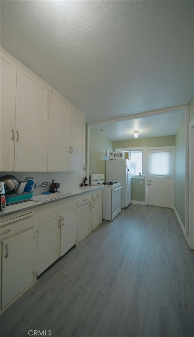 kitchen featuring a textured ceiling, white appliances, light hardwood / wood-style floors, and white cabinetry