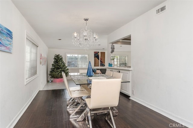 dining area featuring dark wood-type flooring and an inviting chandelier