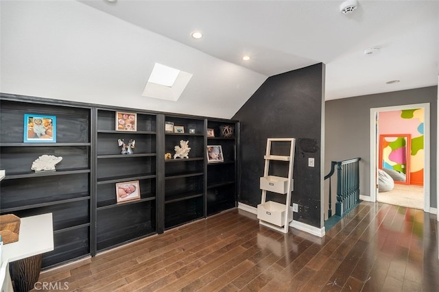 interior space with dark hardwood / wood-style flooring and lofted ceiling with skylight