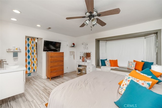 bedroom featuring light hardwood / wood-style flooring, ceiling fan, and sink