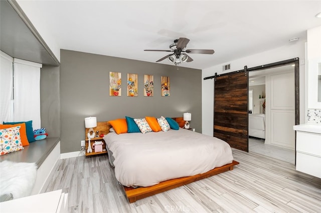 bedroom featuring ceiling fan, a barn door, and light hardwood / wood-style floors