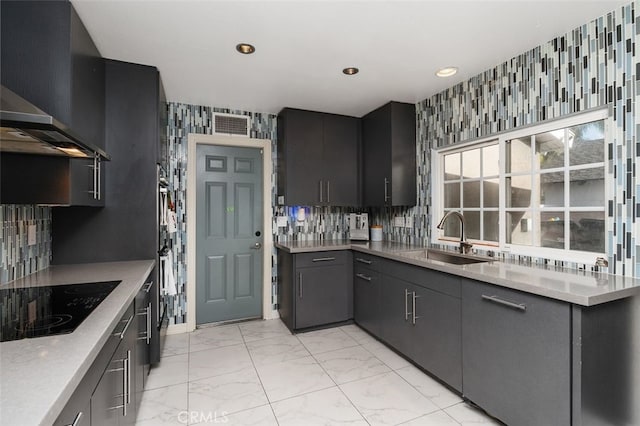 kitchen with black electric stovetop, wall chimney exhaust hood, sink, and tasteful backsplash