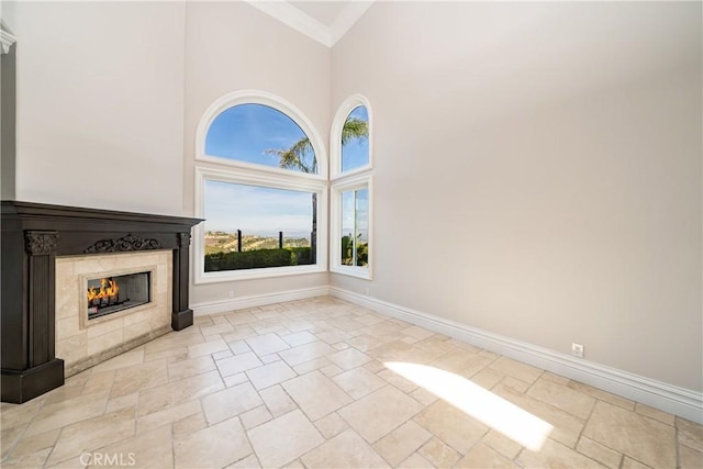 unfurnished living room featuring a tiled fireplace, a towering ceiling, and ornamental molding