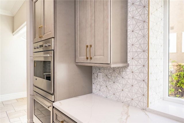 kitchen featuring light stone countertops, stainless steel double oven, and ornamental molding