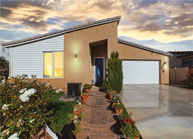 view of front of home with a garage, driveway, fence, and stucco siding