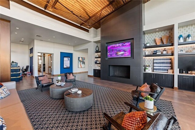 living room featuring a large fireplace, wood ceiling, and a high ceiling