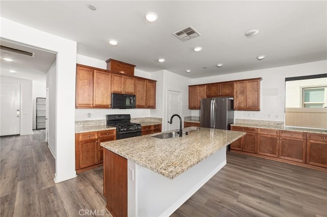 kitchen with brown cabinets, visible vents, and black appliances