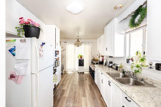 kitchen with white cabinets, white fridge, sink, and hanging light fixtures